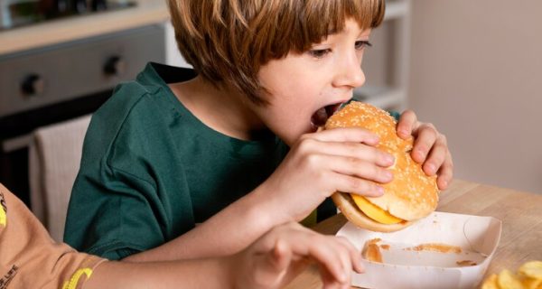 crianca-comendo-hamburguer-em-casa_23-2148914532