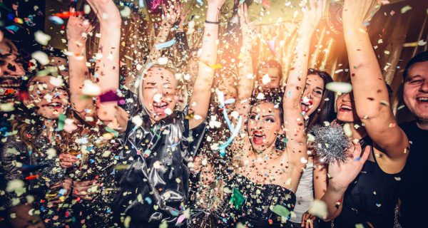 Confetti falling over a smiling group of people on a dance floor of a nightclub