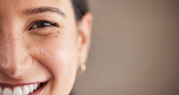 Face of beautiful mixed race woman smiling with white teeth.  Portrait of a woman's face with brown eyes and freckles posing with copy-space. Dental health and oral hygiene