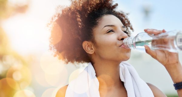 Cropped shot of a young woman enjoying a bottle of water while out for a run