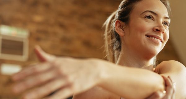 low-angle-view-happy-athletic-woman-warming-up-stretching-her-arm-home